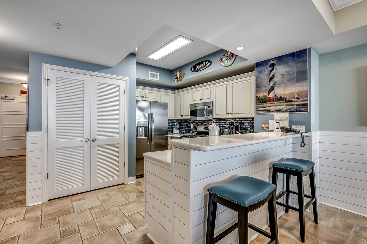 A contemporary kitchen area featuring a spacious island with stools, modern appliances, and bright decorative touches. The setup is perfect for group cooking, casual breakfasts, or festive holiday celebrations, emphasizing the role of food and conversation in building memories.