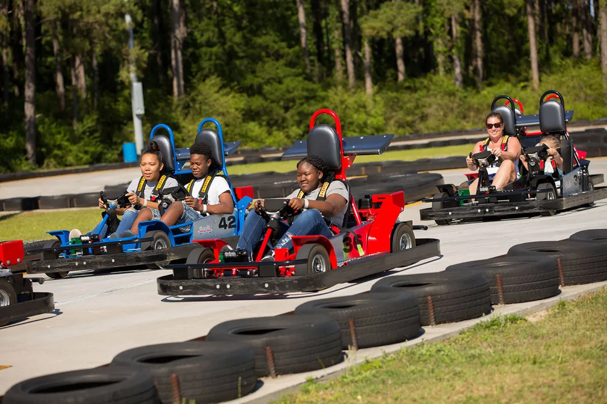 An action-packed exterior scene at a local go-kart racetrack, with families and groups of friends eagerly racing around the track. The joyful expressions and dynamic environment showcase the thrill and energy of kid-approved nearby attractions.