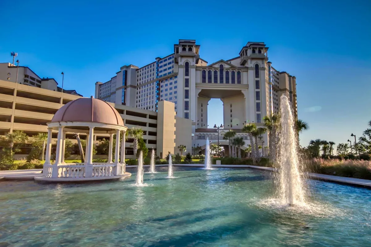 This exterior image highlights a tranquil outdoor area with a beautiful fountain, a charming gazebo, and the impressive North Beach Towers building in the background. Lush landscaping and serene water features invite relaxation and outdoor enjoyment.